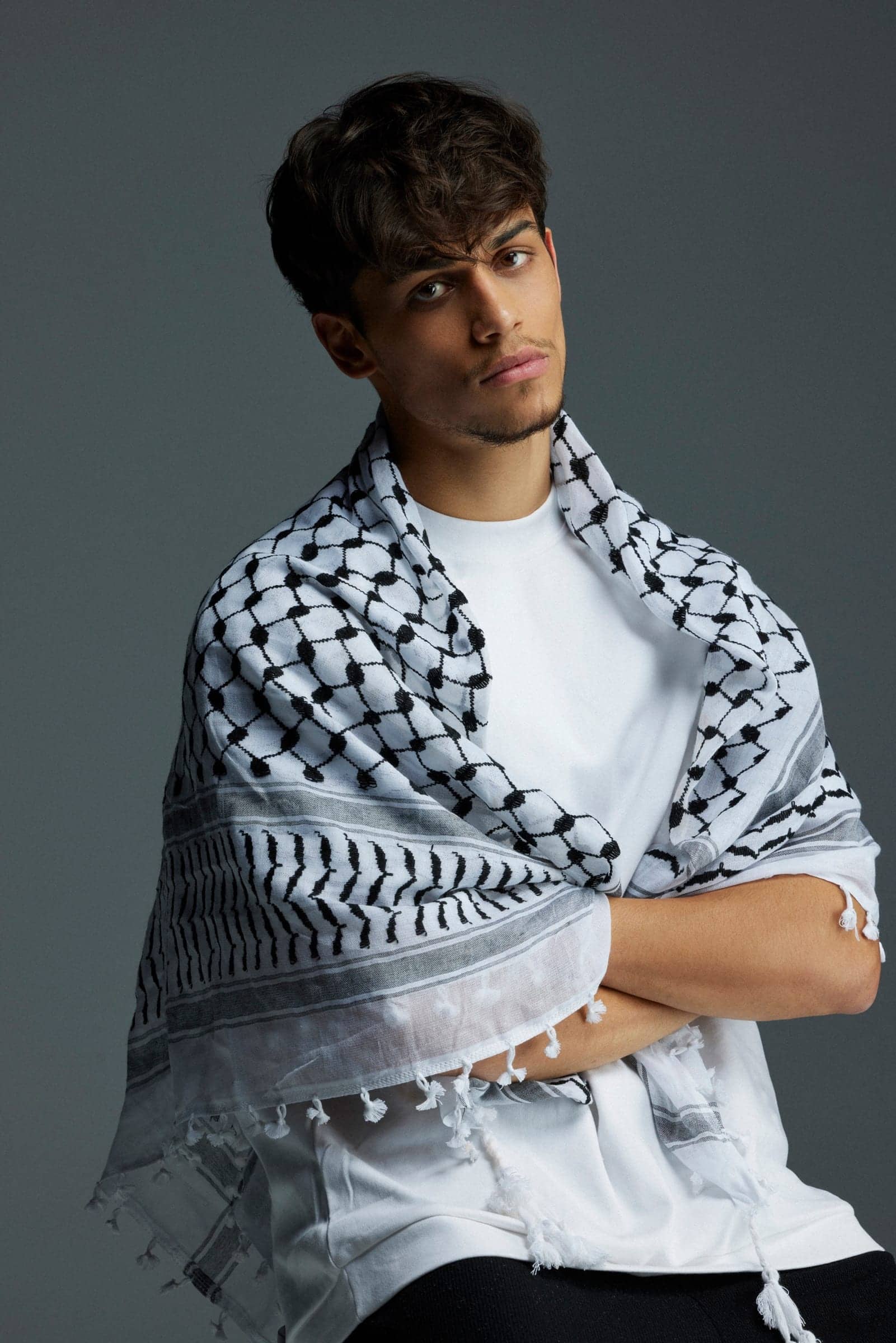 Harris J with a black-and-white keffiyeh draped over his shoulders, arms crossed
