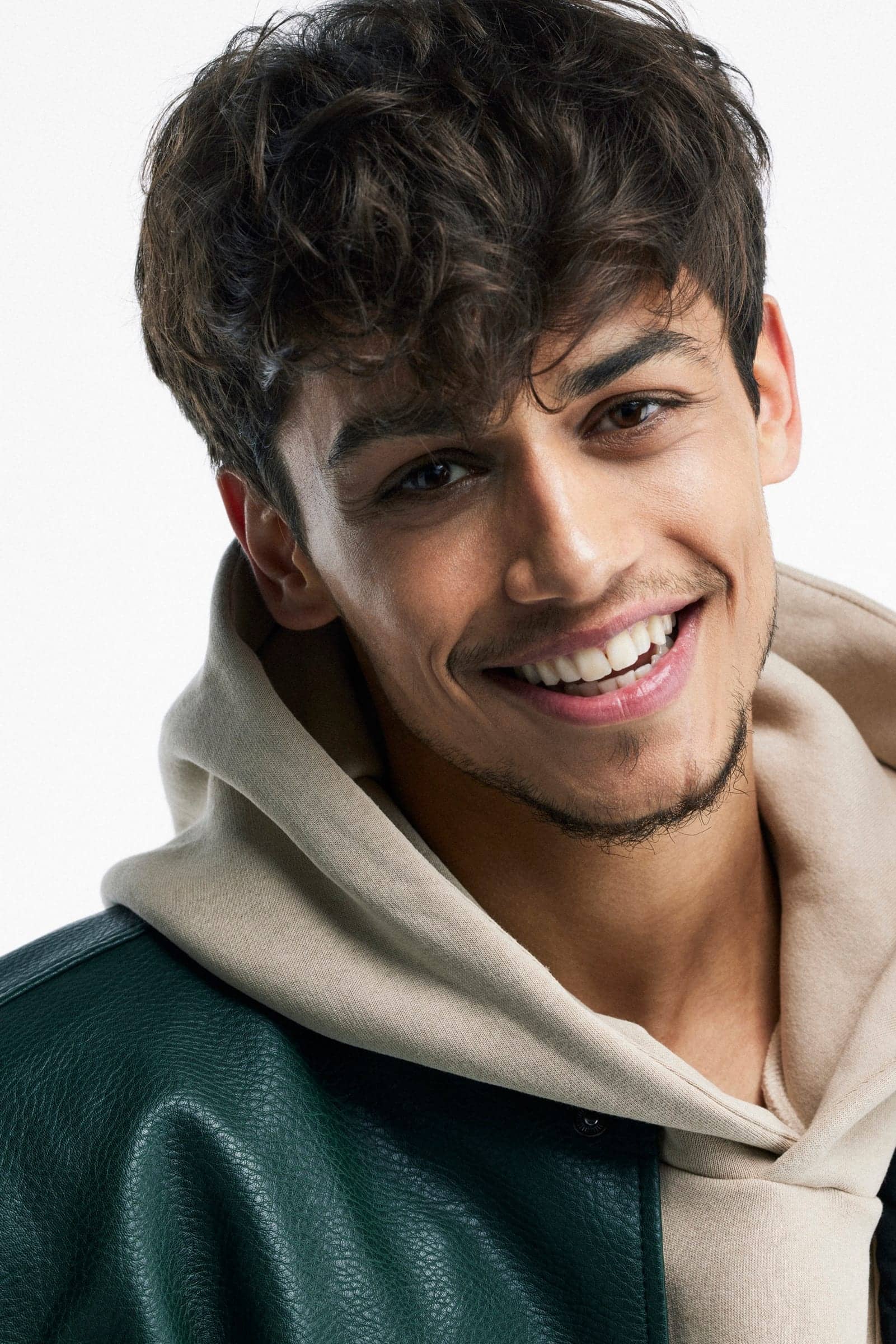 Close-up of Harris J laughing, in a cream hoodie and green leather jacket
