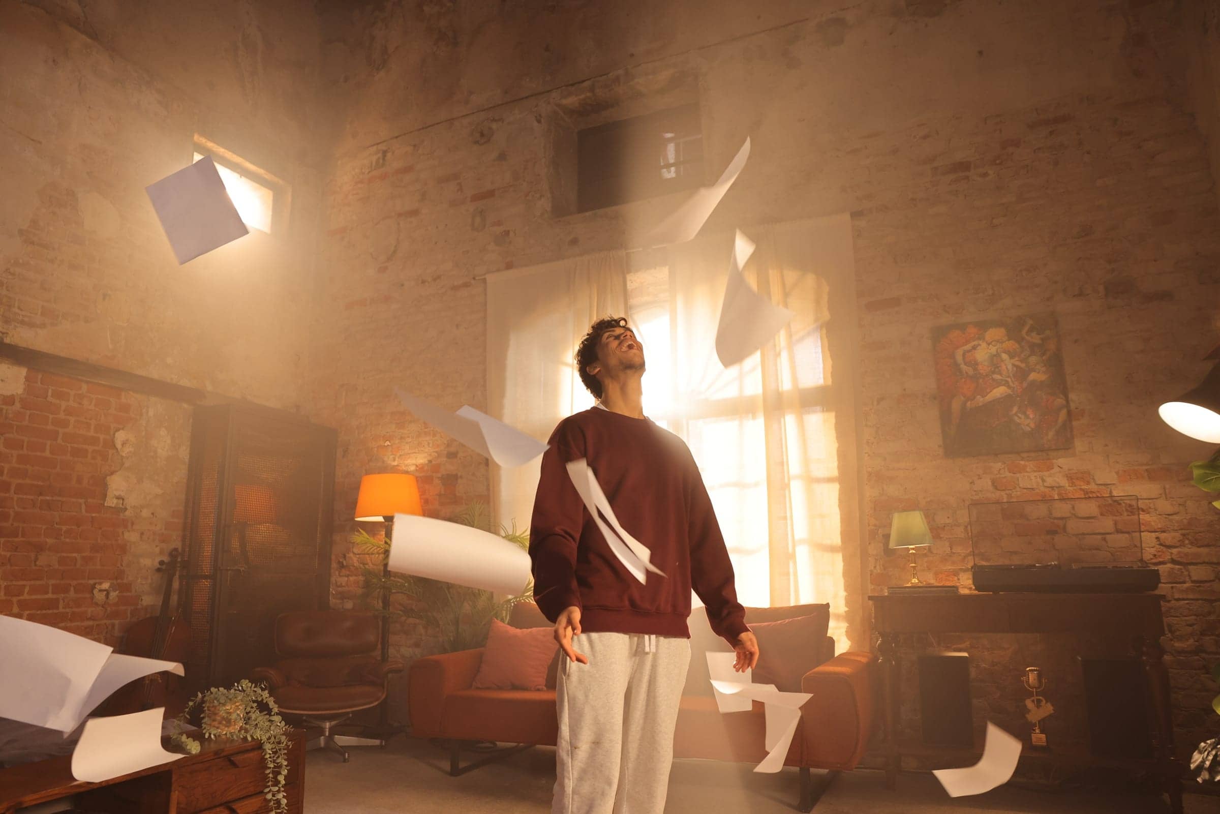 Harris J looking up joyfully as sheets of paper fly around him